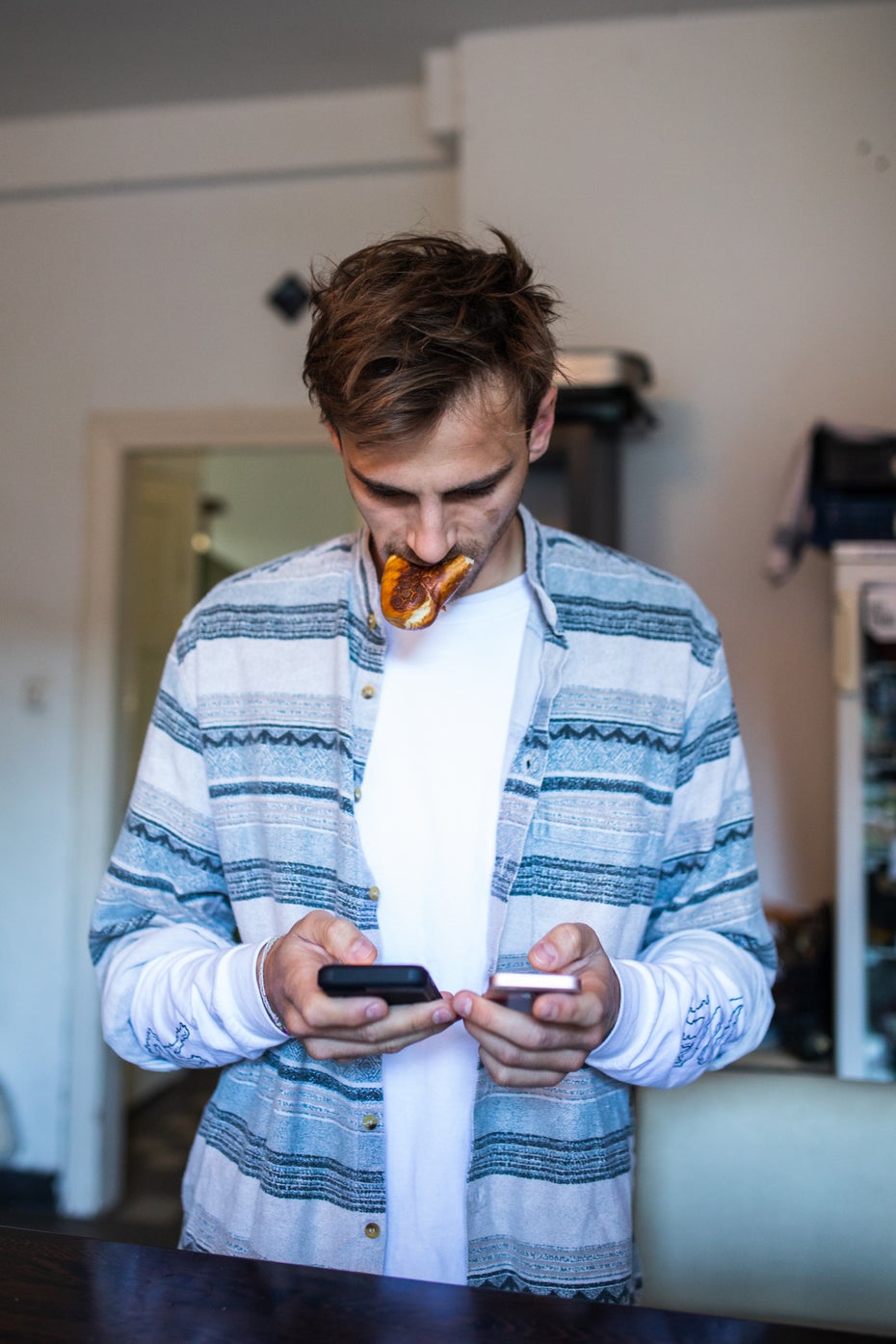 Zwei Smartphones in den Händen, ein Brötchen im Mund: Multitasking bei Fynn Kliemann. (Foto: © Jan-Helge Petri)