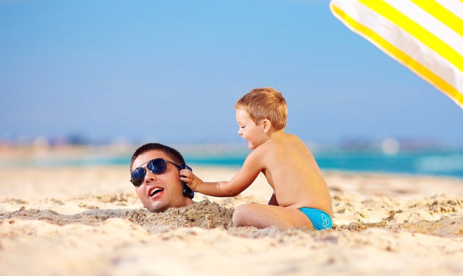 Auch Smartphones sollten gut vor Hitze und der Sonne geschützt werden – aber auch vor Sand und Wasser. (Foto: <a href="http://www.shutterstock.com/de/pic-157057139/stock-photo-happy-kid-helping-father-in-sand-talk-on-the-mobile-phone.html">Shutterstock</a>)