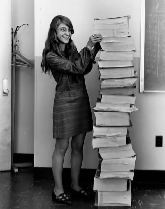 Margaret Hamilton, eine der leitenden Entwicklerinnen der Apollo-11-Mission neben dem ausgedruckten Code für den Apollo Guidance Computer, der jetzt auf GitHub eingesehen werden kann. (Quelle: Wikipedia)