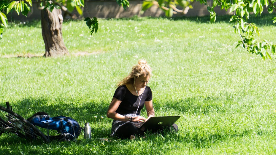 (Foto: Shutterstock / Tivanova) Coliving: Menschen mit Laptop am Dorfteich