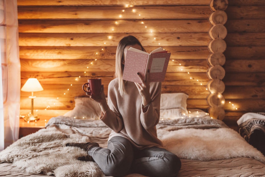 Wer mehr Bücher lesen will, muss sich auch eine Wohlfühl-Atmosphäre schaffen. (Foto: <a href="https://www.shutterstock.com/image-photo/woman-relaxing-reading-book-on-cozy-1230755437">Shutterstock</a>)