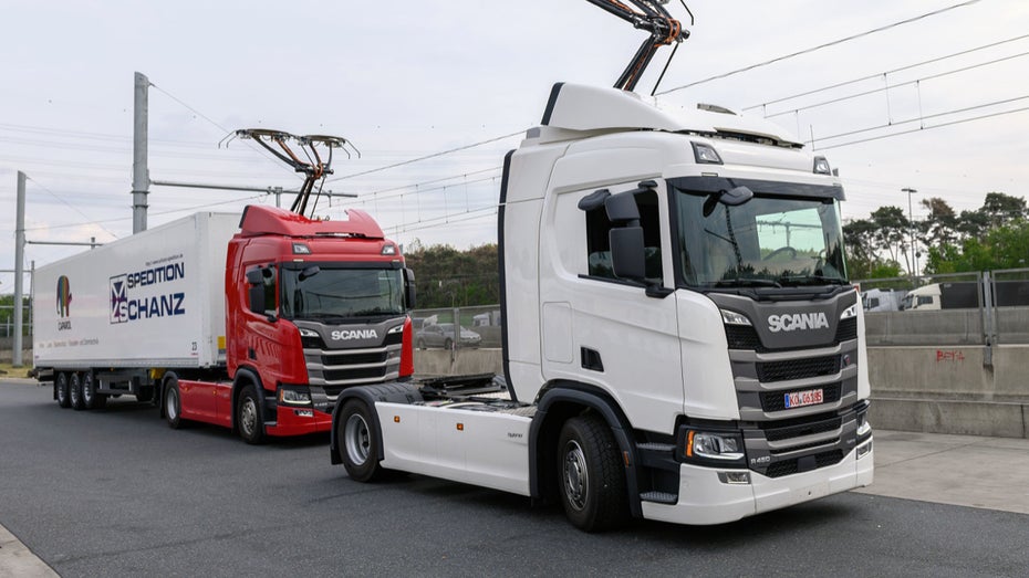 Zwei Scania-R450-Hybrid-Zugmaschinen stehen vor Beginn der Inbetriebnahme der ersten deutschen Teststrecke für E-Lastwagen mit Oberleitung an einer Raststätte der Autobahn 5. (Foto: Silas Stein / dpa) Pilotprojekt: E-Autobahn für Lastwagen in Deutschland geht in Betrieb