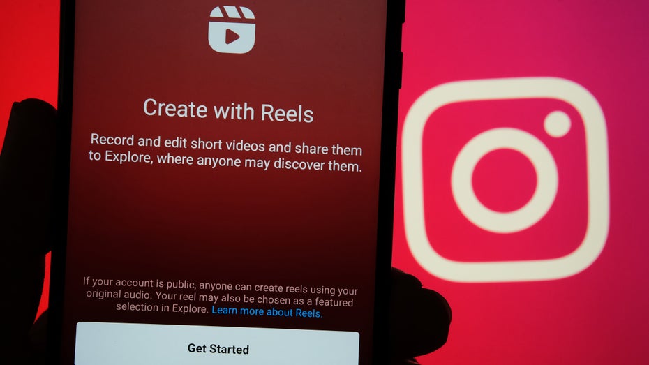 Smartphone mit dem Reels-Startbildschirm vor dem Instagram-Logo