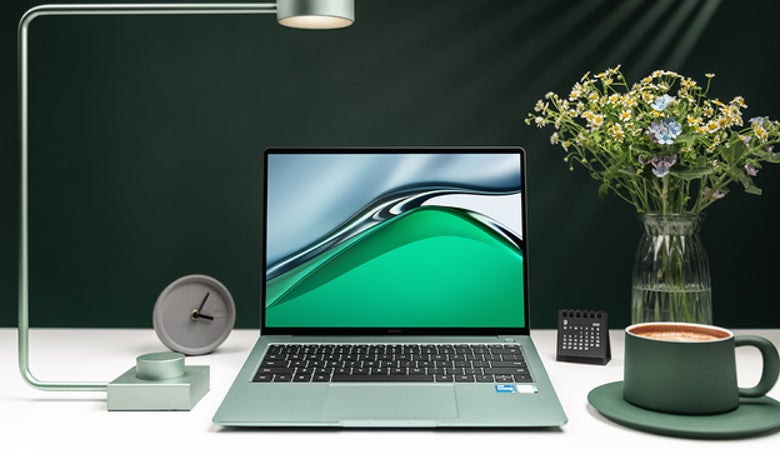 Das HUAWEI MateBook 14s auf einem minimalistisch eingerichteten, weißen Schreibtisch vor dunkelgrau-schwarzem Hintergrund. Dazu: Ein Wecker, eine Schreibtischlampe, ein kleiner Kalender, eine Kaffeetasse mit Untersetzer sowie eine Vase mit Schnittblumen