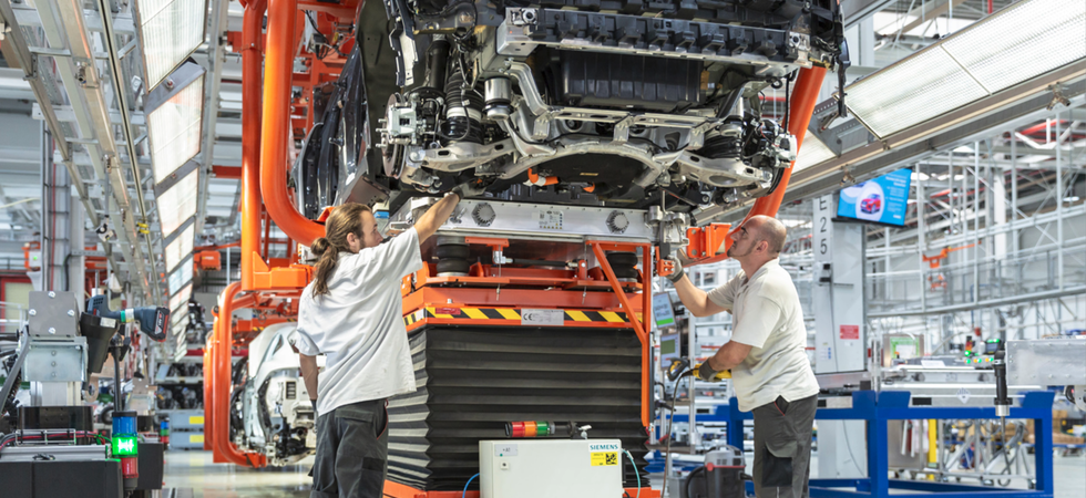Zwei Mitarbeiter der Firma Magna arbeiten an einem noch nicht fertiggestellten Fahrzeug in der Produktionsstraße