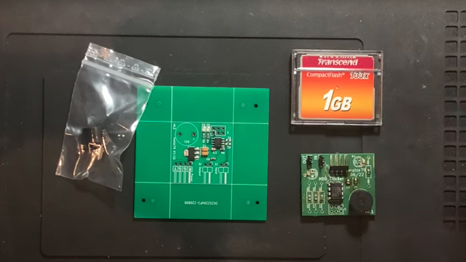 Rechts unten im Bild ist der HDD-Klicker zu sehen, mittig eine größere Version von ihm. Die verwendete Speicherkarte befindet sich rechts oben im Bild, auf der linken Seite sind in der Plastiktüte Pieper und elektrische Steckverbinder. (Screenshot: Roo42 – Youtube/t3n) Sound für SSD: Techbastler bringt Festplattengeräusche zurück