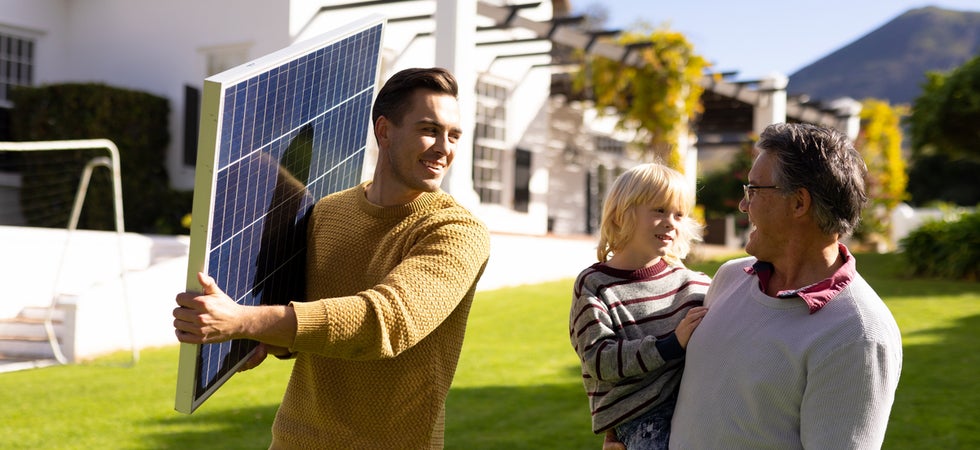 Ein weißer Vater trägt eine Solaranlage, der Opa hält währenddessen ein junges Kind. Die Sone scheint