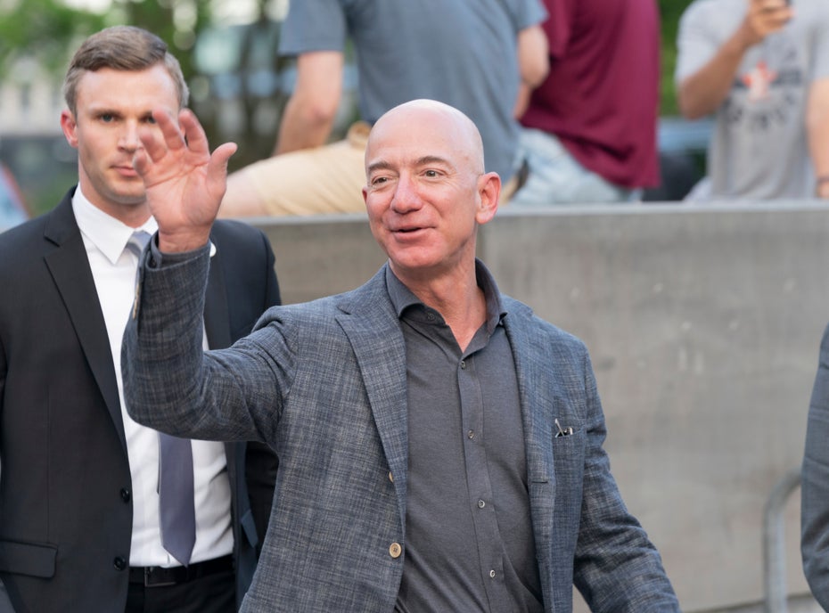 Jeff Bezos winkt auf einer Veranstaltung Menschen zu.