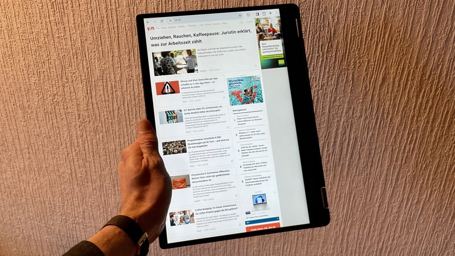 Eine Hand hält ein großes Tablet.