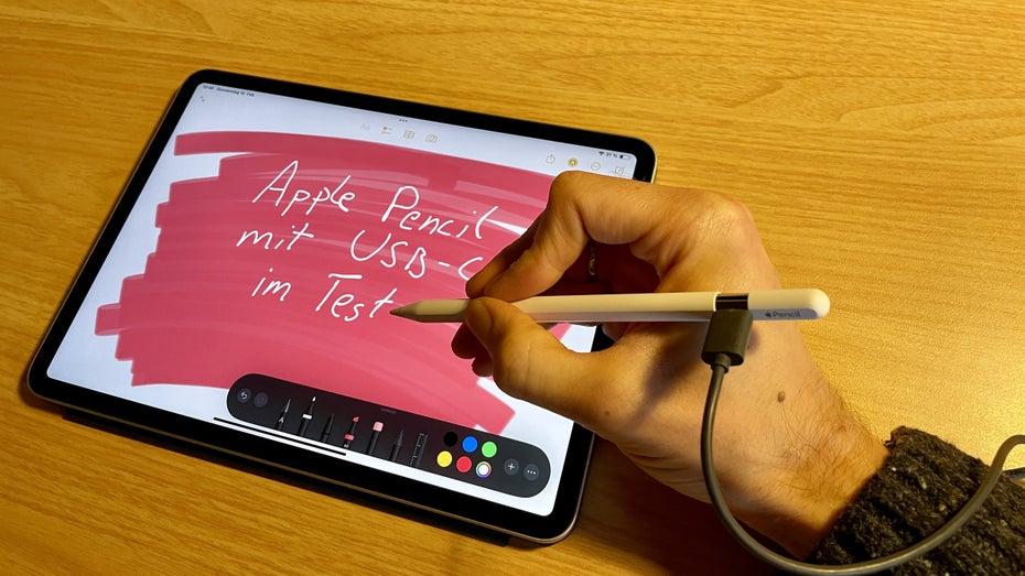 Eine Hand hält den Apple Pencil mit eingestecktem USB-C-Kabel.