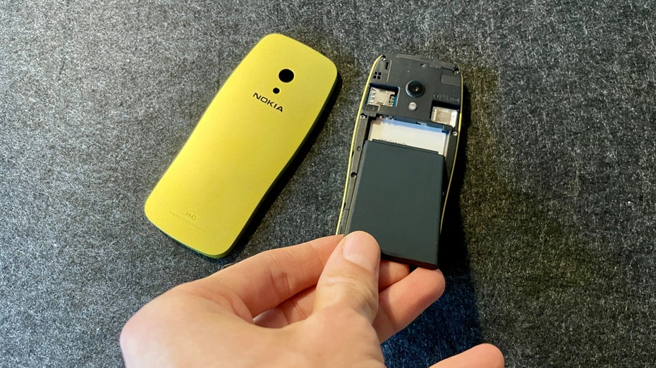 Eine Hand legt einen Akku ins das Nokia 3210 ein.