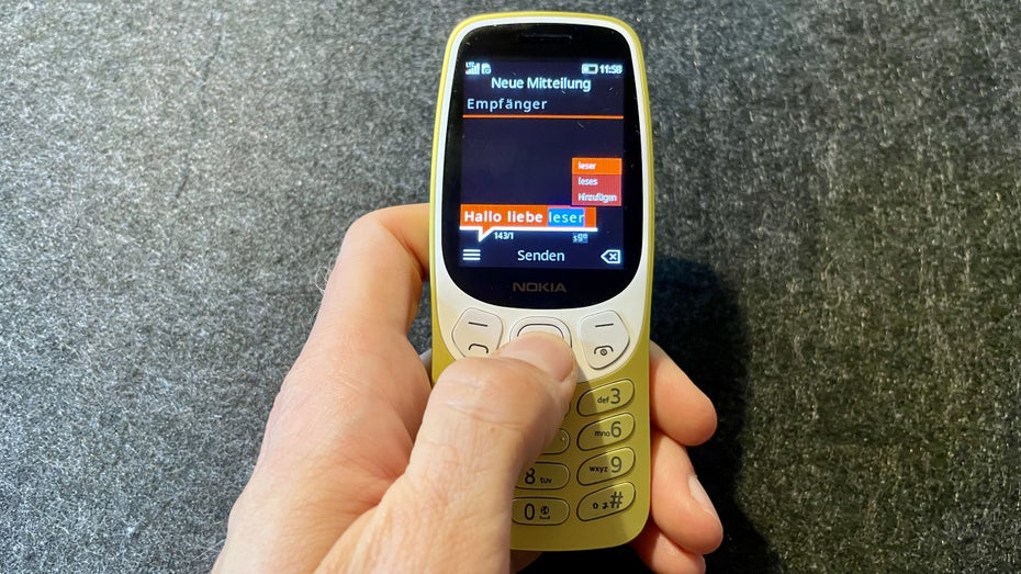 Eine Hand tippt eine Nachricht auf dem Nokia 3210.
