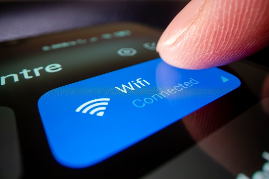 Ein Finger, der auf ein Smartphone tippt. Auf dem Display ist die Schaltfläche für Wi-Fi zu sehen.