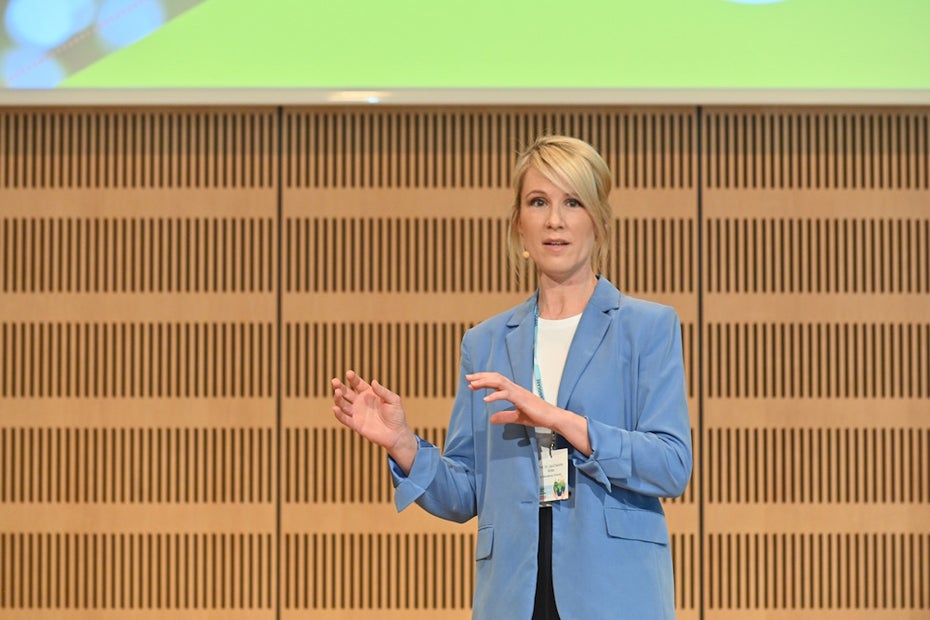 Lisa-Charlotte Wolter is dressed in a blue blazer against a brown background and a short break.