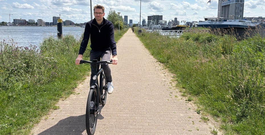 Ein Mensch fährt auf einem Fahrrad am Kanal entlang.