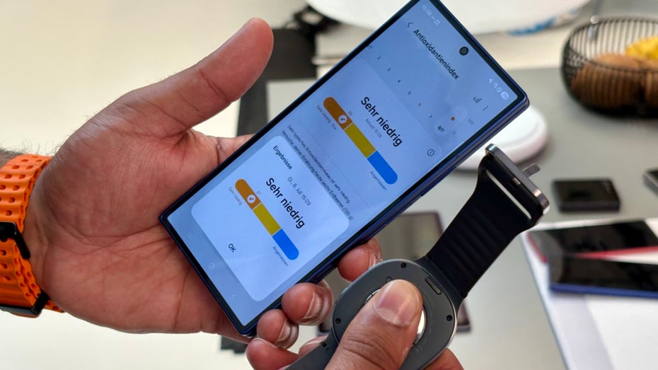 Ein Mensch hält ein Smartphone und eine Uhr.